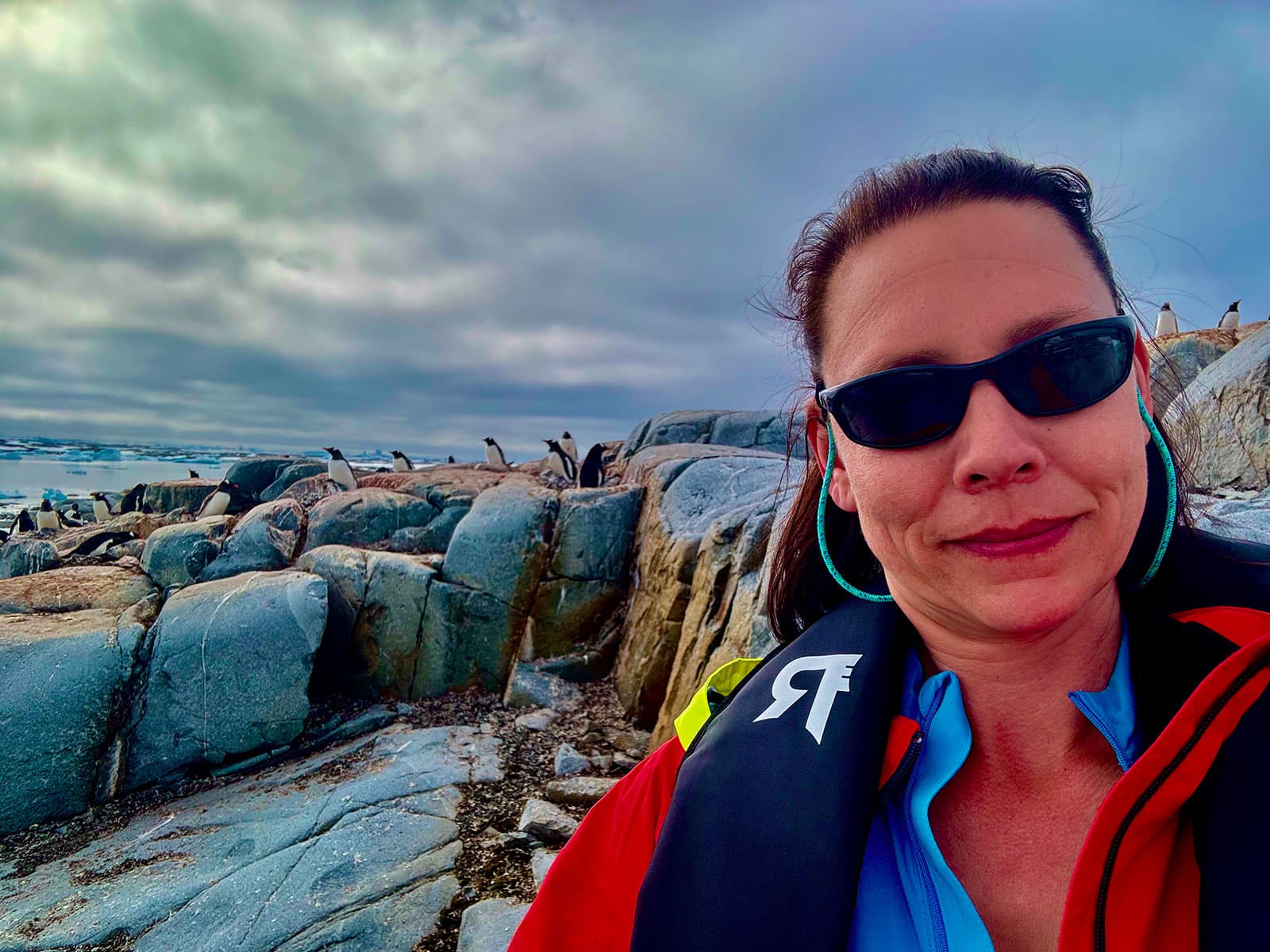 Jennifer with penguins on rocks behind her