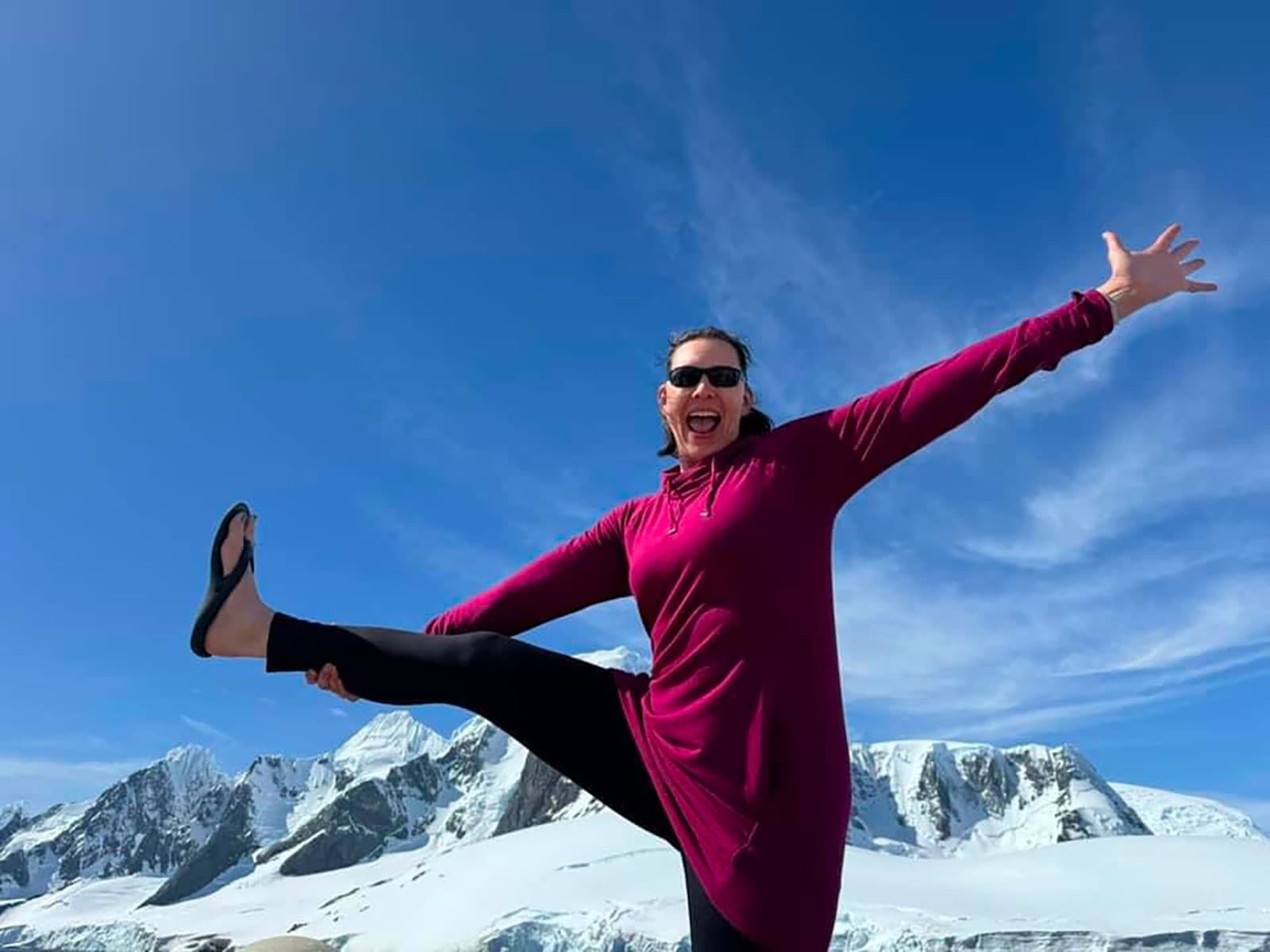 Jennifer celebrating on Antarctic snow beneath a blue sky