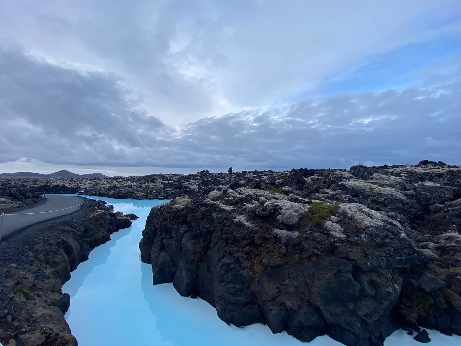 Milky blue lagoon water winding through dark lava rocks