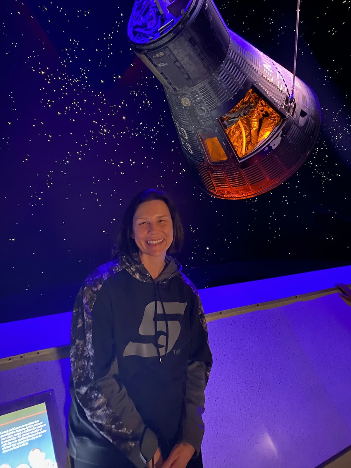 Jennifer standing beneath a suspended spacecraft exhibit