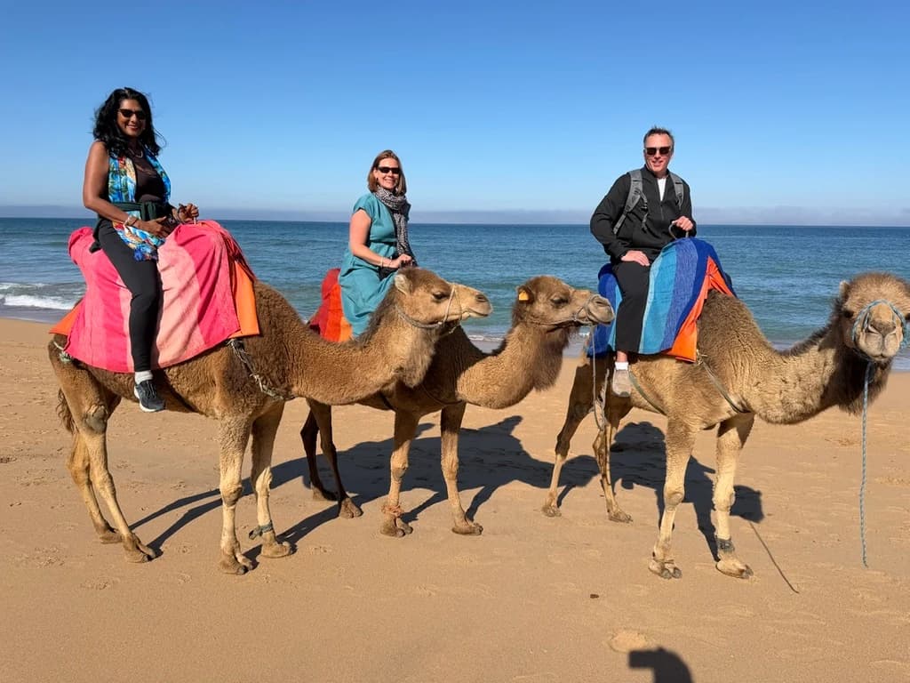 Lina, Jennifer, and Kevin riding camels beside the Atlantic Ocean