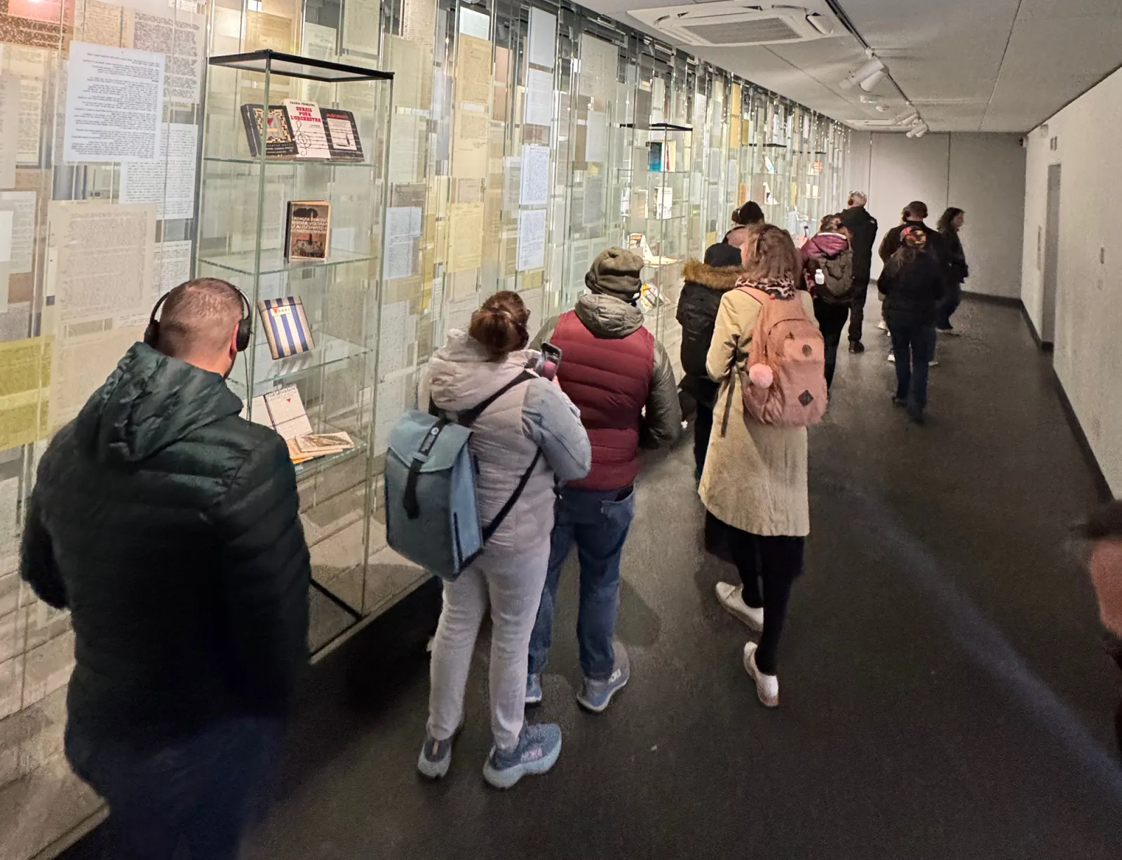 Visitors viewing historical records in glass displays inside Auschwitz I