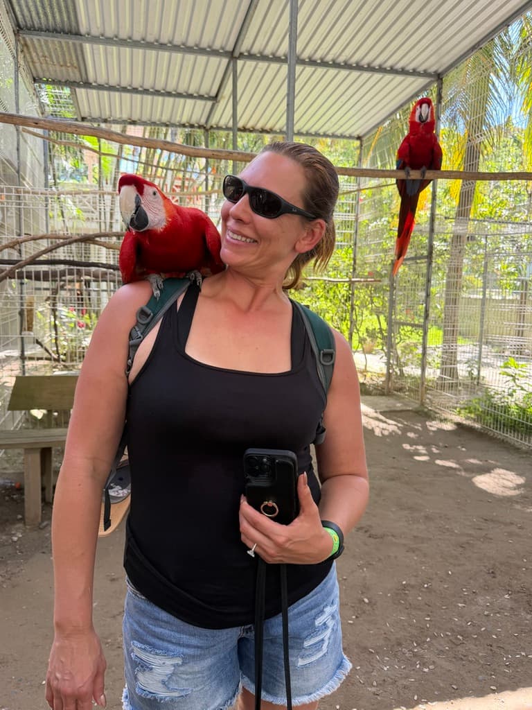 Jennifer with a macaw perched on her shoulder in an enclosed setting