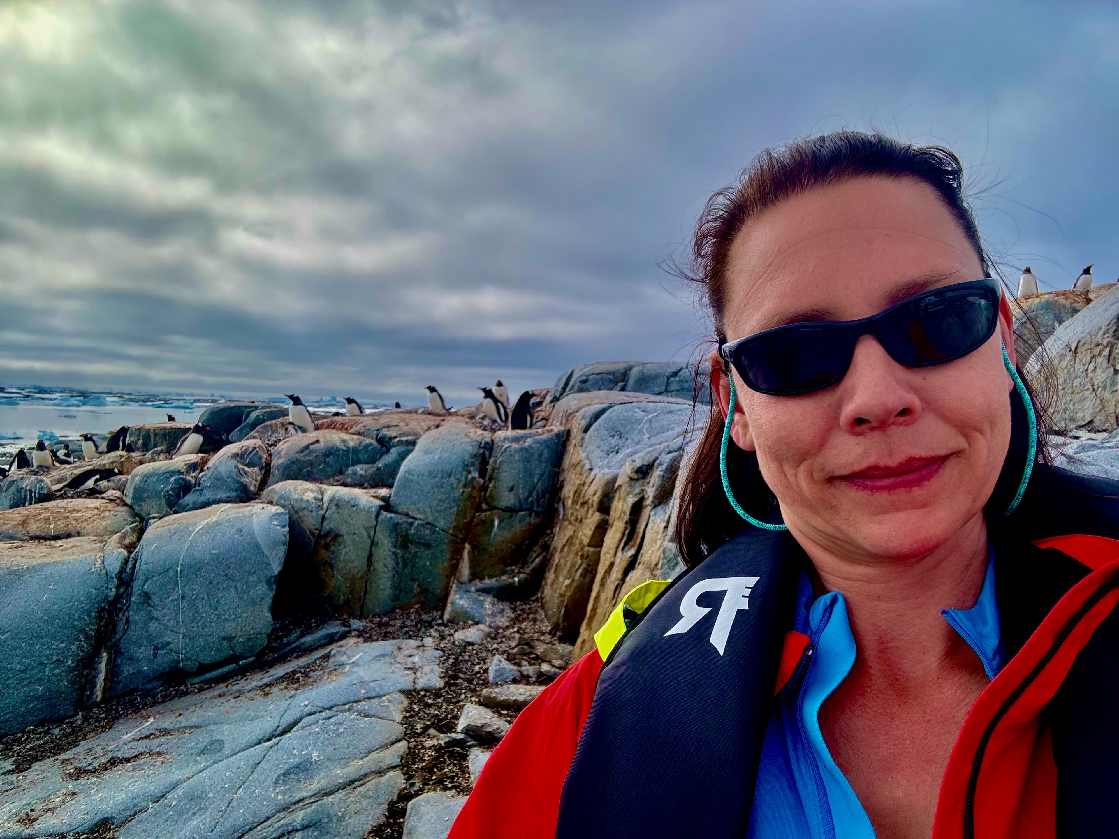 Jennifer at a distance from penguins on an Antarctic shoreline